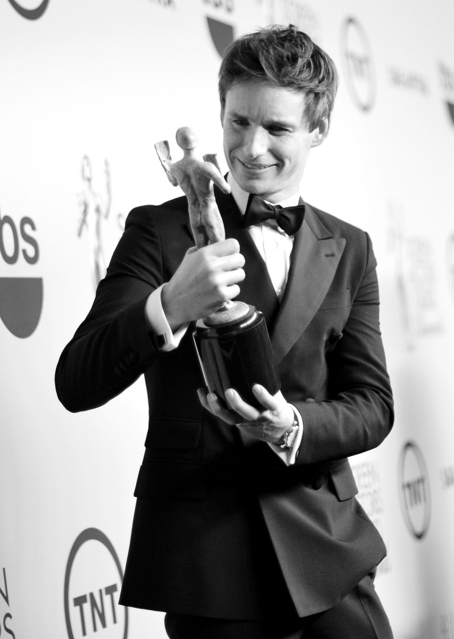 Eddie Redmayne in black-and-white inspecting his SAG Award